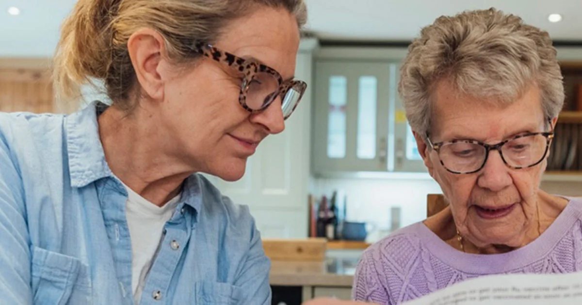 An older woman and her daughter going through paperwork before an aged care assessment.