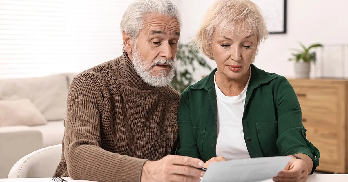 An older couple at their dining table going through financial paperwork together