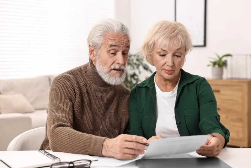 An older couple at their dining table going through financial paperwork together
