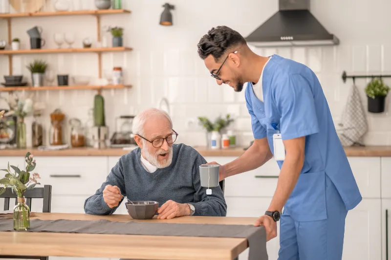 A care worker helping an older man in his kitchen at home